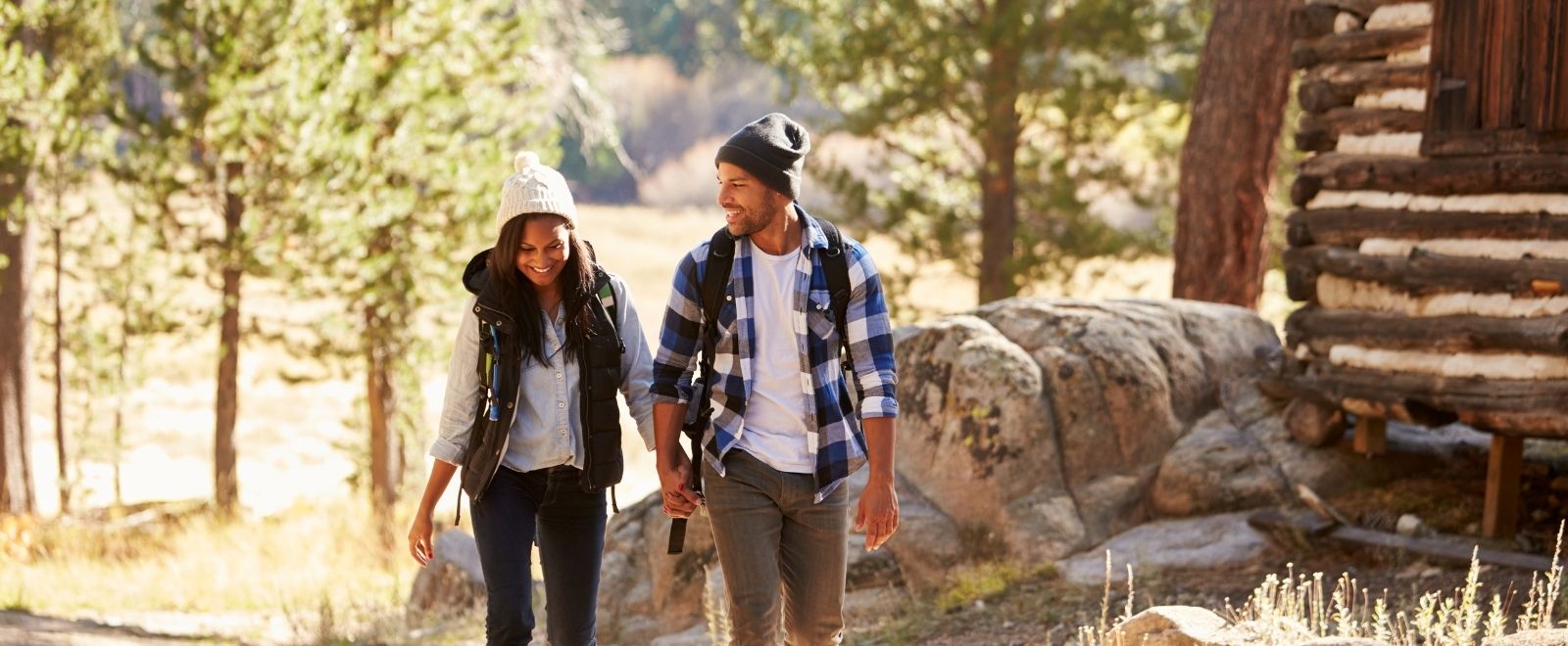 Couple walking in the woods outside of log cabin