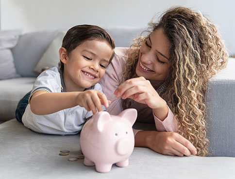 Mother and son saving coins in a piggy bank