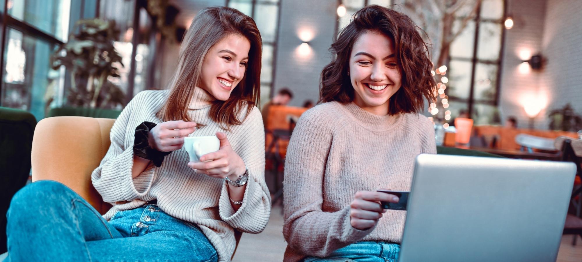 two women online shopping in a coffee shop earning cash back rewards